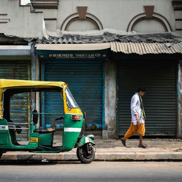 インドの街角でトゥクトゥクのそばを歩く男性の姿